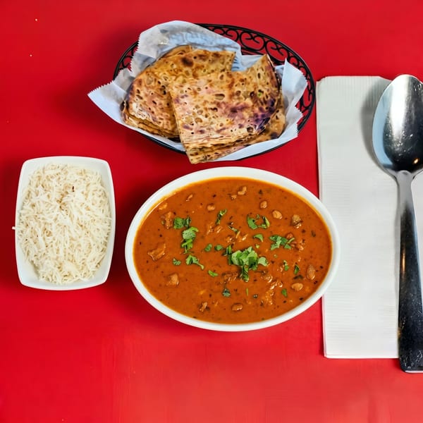 Overhead view of Indian curry, basmati rice, and naan bread on a vibrant red table.